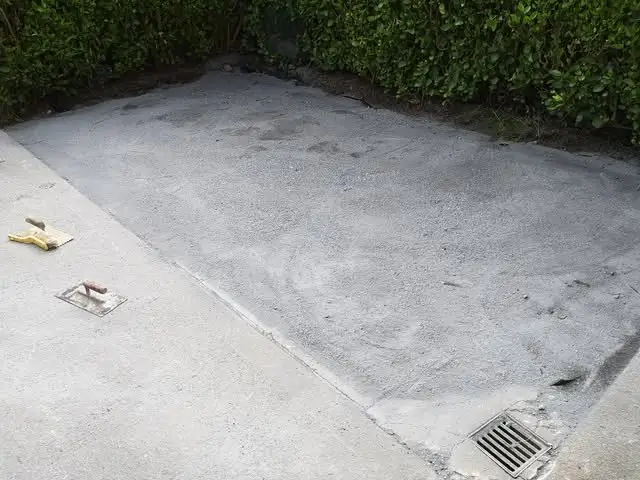 Before: bare grey concrete yard with a drain