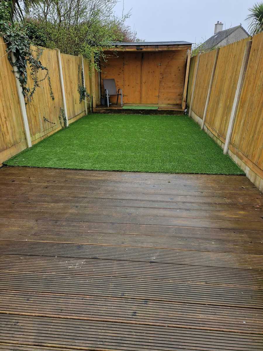 Timber decking in the foreground with artificial grass beyond