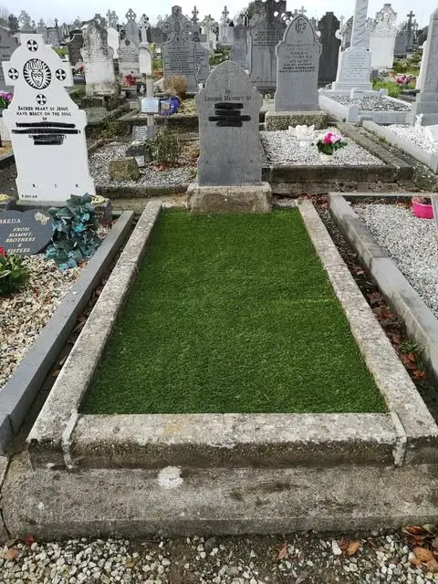 After: the same grave covered in neat green artificial grass