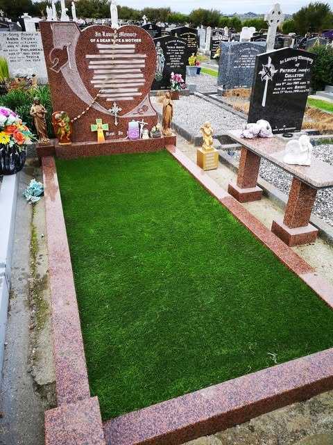 Grave with a red granite headstone and surround, covered in green artificial grass