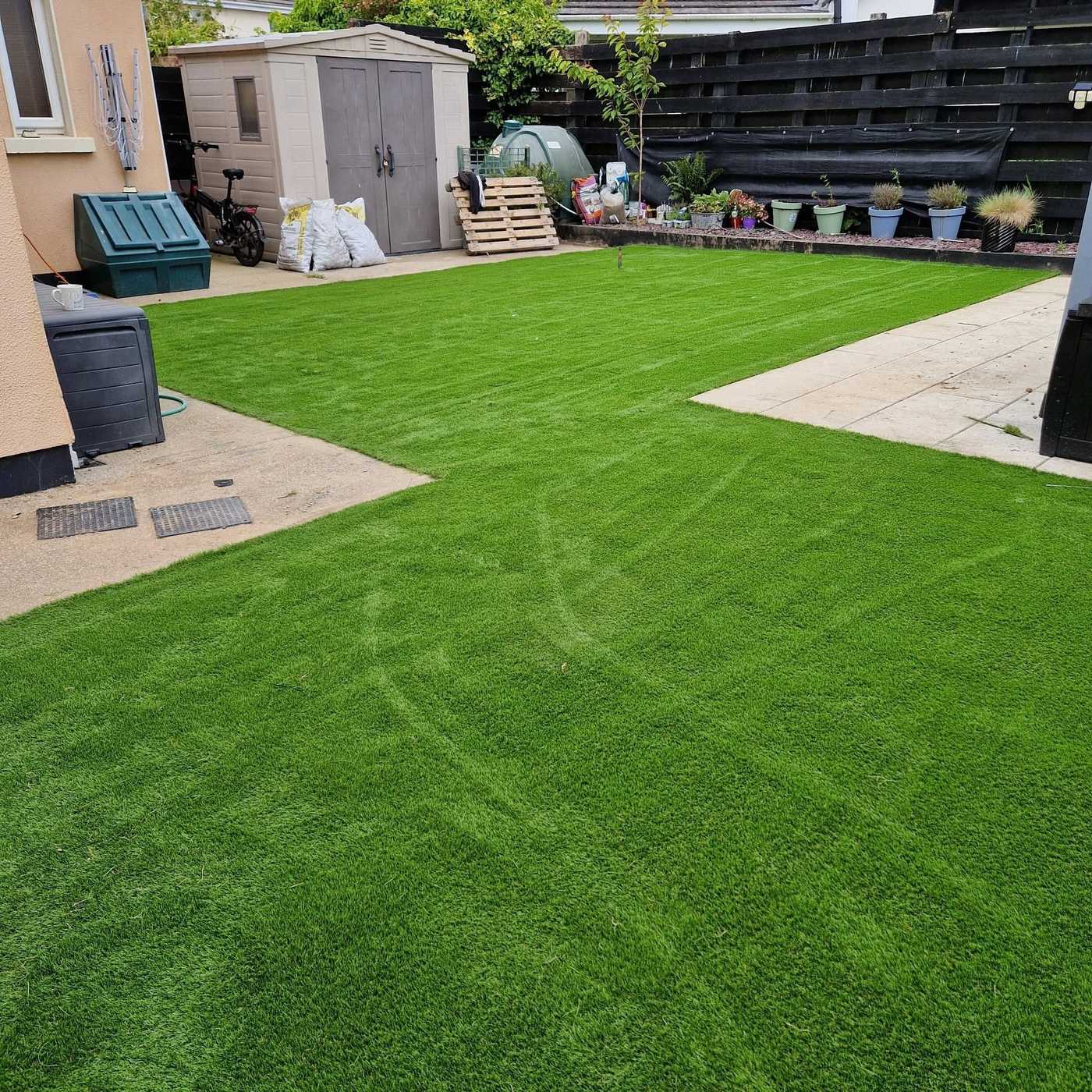 Large back garden with artificial lawn, patio slabs and a garden shed