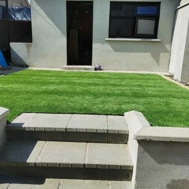 Artificial lawn at the top of concrete patio steps behind a house
