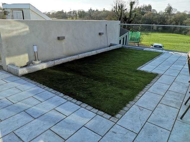 Wider view of the lawn and paving with fields beyond the garden wall