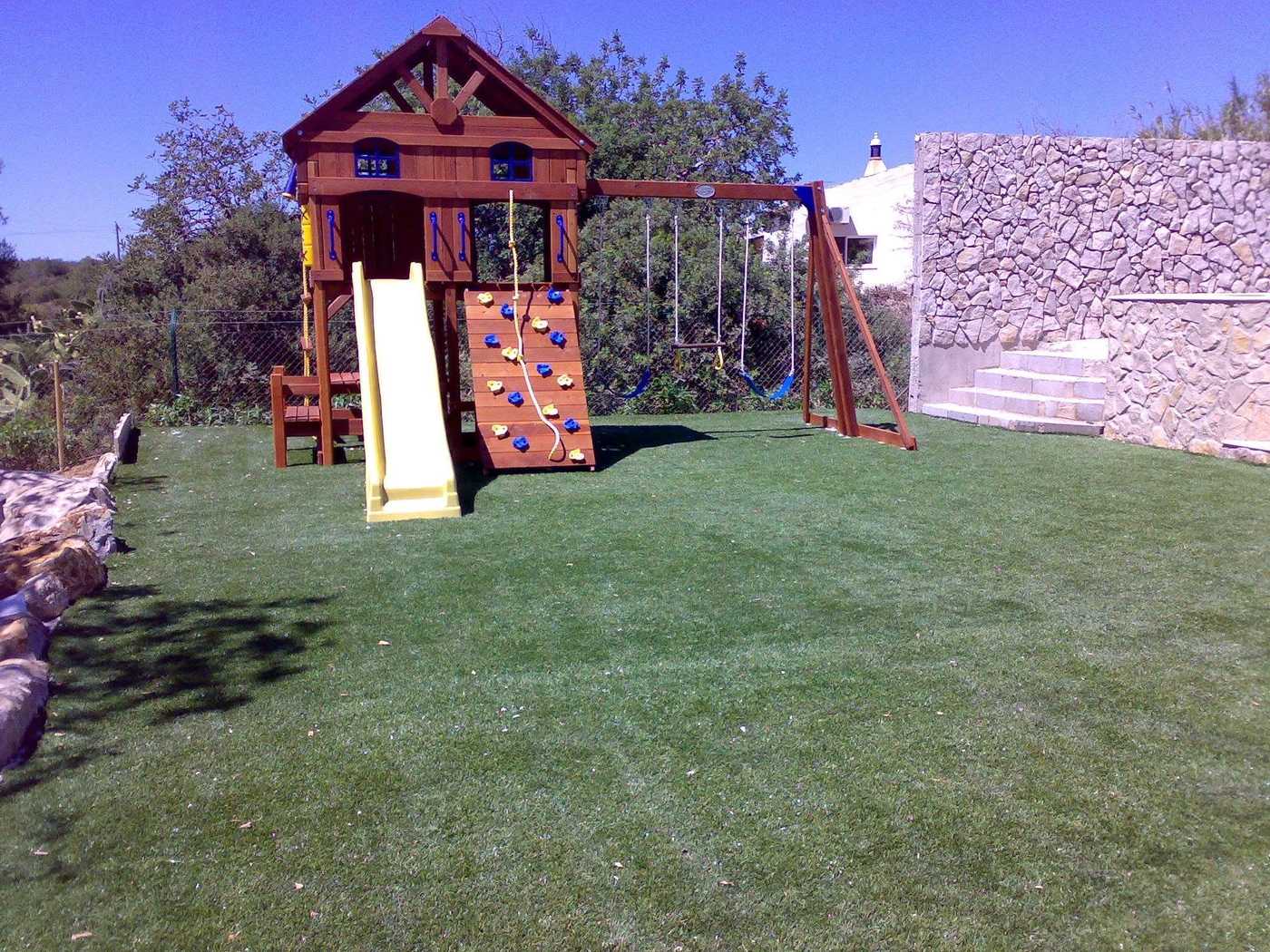 Timber play fort with a yellow slide standing on artificial grass
