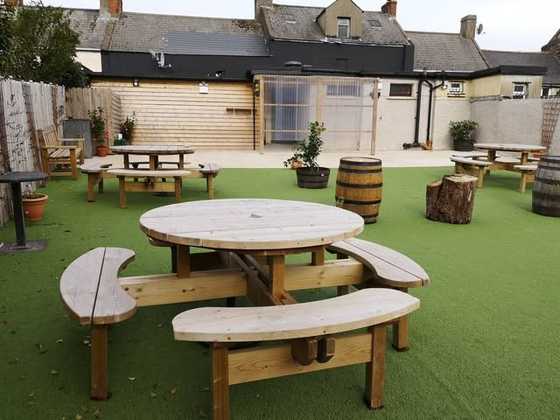 Pub beer garden with round timber picnic benches on artificial grass